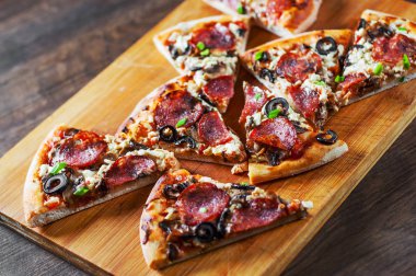 Mozzarella peyniri, salam, biber, biber, zeytin, baharat ve mantar pizza. Ahşap masa arka plan üzerinde İtalyan pizza