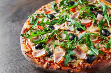 Pizza Mozzarella peyniri, mantar, jambon, domates sosu, biber, zeytin, baharatlar ve taze roka. Ahşap masa arka plan üzerinde İtalyan pizza