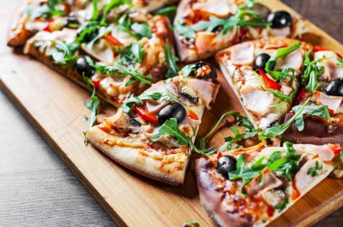 Pizza Mozzarella peyniri, mantar, jambon, domates sosu, biber, zeytin, baharatlar ve taze roka. Ahşap masa arka plan üzerinde İtalyan pizza