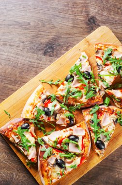 Pizza Mozzarella peyniri, mantar, jambon, domates sosu, biber, zeytin, baharatlar ve taze roka. Ahşap masa arka plan üzerinde İtalyan pizza