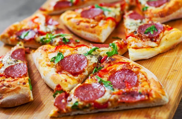 Mozzarella peyniri, salam, domates, biber, baharat ve taze roka ile biberli Pizza. Ahşap masa arka plan üzerinde İtalyan pizza