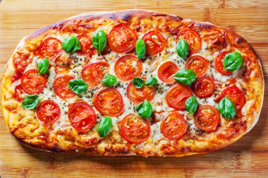 Oval Pizza Mozzarella peyniri, domates, biber, baharat ve taze fesleğen. İtalyan pizza. Pizza Margherita veya ahşap masa arka plan üzerinde Margarita