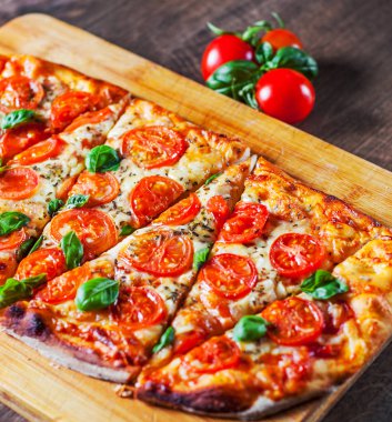 Oval Pizza Mozzarella peyniri, domates, biber, baharat ve taze fesleğen. İtalyan pizza. Pizza Margherita veya ahşap masa arka plan üzerinde Margarita