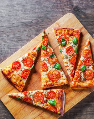 Pizza Mozzarella peyniri, domates, biber, baharat ve taze fesleğen. İtalyan pizza. Pizza Margherita veya ahşap masa arka plan üzerinde Margarita