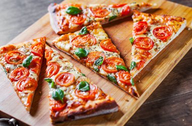 Pizza Mozzarella peyniri, domates, biber, baharat ve taze fesleğen. İtalyan pizza. Pizza Margherita veya ahşap masa arka plan üzerinde Margarita