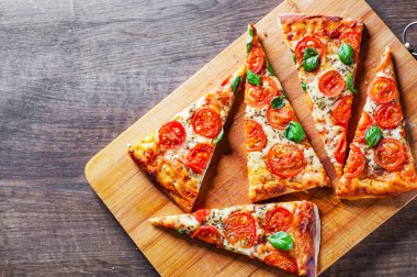 Pizza Mozzarella peyniri, domates, biber, baharat ve taze fesleğen. İtalyan pizza. Pizza Margherita veya ahşap masa arka plan üzerinde Margarita