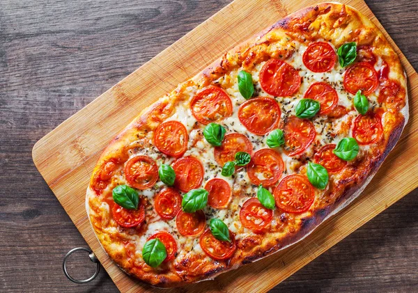 Oval Pizza Mozzarella peyniri, domates, biber, baharat ve taze fesleğen. İtalyan pizza. Pizza Margherita veya ahşap masa arka plan üzerinde Margarita