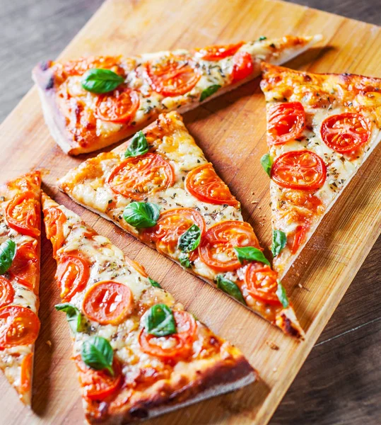 Pizza Mozzarella peyniri, domates, biber, baharat ve taze fesleğen. İtalyan pizza. Pizza Margherita veya ahşap masa arka plan üzerinde Margarita