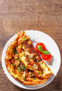 ahşap masa üzerinde beyaz bir tabak içinde pastırmalı omlet