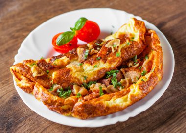 ahşap masa üzerinde beyaz bir tabak içinde pastırmalı omlet