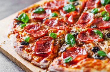 Pepperoni Pizza Mozzarella peyniri, salam, domates, zeytin, biber, baharat ve taze fesleğen. Ahşap masa arka plan üzerinde İtalyan pizza