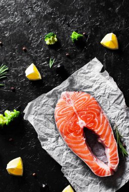 brokoli, limon, zeytin, biber ve koyu arka plan üzerinde aromatik otlar ile taze Çiğ somon steak. kopya alanı ile. Üstten Görünüm