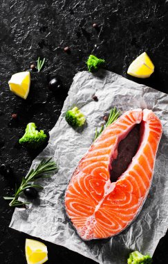 brokoli, limon, zeytin, biber ve koyu arka plan üzerinde aromatik otlar ile taze Çiğ somon steak. kopya alanı ile. Üstten Görünüm