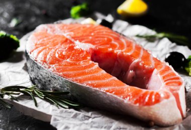 taze Çiğ somon biftek brokoli, limon, zeytin, biber ve koyu arka plan üzerinde aromatik otlar ile