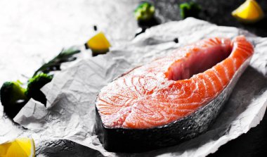 taze Çiğ somon biftek brokoli, limon, zeytin, biber ve koyu arka plan üzerinde aromatik otlar ile