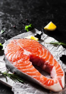 taze Çiğ somon biftek brokoli, limon, zeytin, biber ve koyu arka plan üzerinde aromatik otlar ile