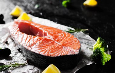 taze Çiğ somon biftek brokoli, limon, zeytin, biber ve koyu arka plan üzerinde aromatik otlar ile