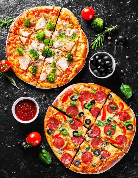 Pepperoni Pizza with Mozzarella cheese, salami, Tomatoes, olive, pepper, Spices and Fresh Basil and Pizza with cheese, salmon fish, broccoli, tomato sauce. two Italian pizza on dark background