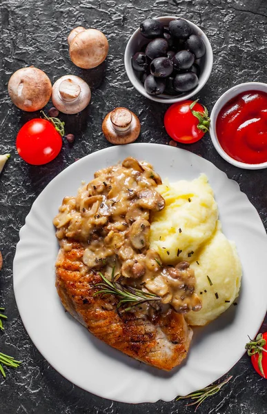 Mantar sos ve patates püresi koyu arka plan üzerinde beyaz plaka ile kavrulmuş tavuk göğsü