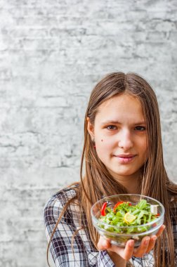 genç genç gri duvar zemin üzerine yeşil sebzeler salata yemek uzun saçlı esmer kız portresi