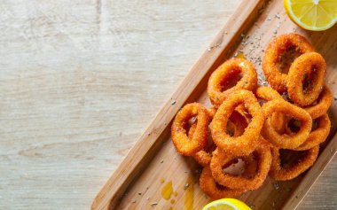 ahşap masa arka plan üzerinde limonlu tava kalamar halkaları kızarmış