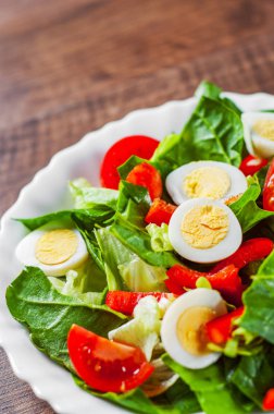 yumurta, biber ve domates ahşap masa arka plan üzerinde beyaz tabak içinde ıspanak salatası