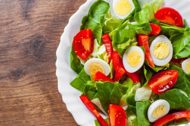 yumurta, biber ve domates ahşap masa arka plan üzerinde beyaz tabak içinde ıspanak salatası