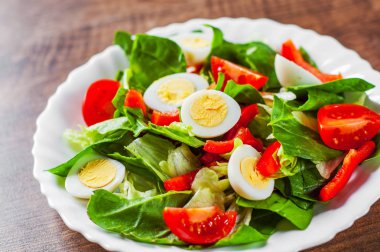yumurta, biber ve domates ahşap masa arka plan üzerinde beyaz tabak içinde ıspanak salatası