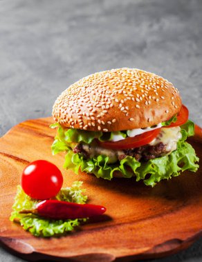 Ahşap tahta üzerinde et, peynir ve sebze ile Burger