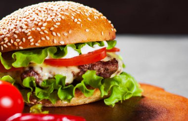 Ahşap tahta üzerinde et, peynir ve sebze ile Burger