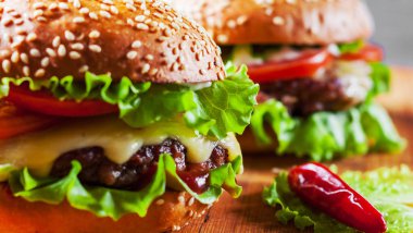 et, peynir ve ahşap tahta üzerinde sebze ile iki burger