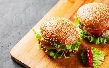 et, peynir ve ahşap tahta üzerinde sebze ile iki burger