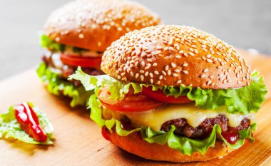 et, peynir ve ahşap tahta üzerinde sebze ile iki burger