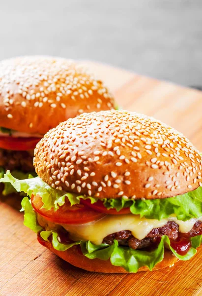 et, peynir ve ahşap tahta üzerinde sebze ile iki burger