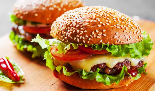 et, peynir ve ahşap tahta üzerinde sebze ile iki burger