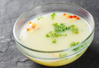 Koyu gri siyah arduvaz arka plan üzerine cam kapta krem tavuk çorbası