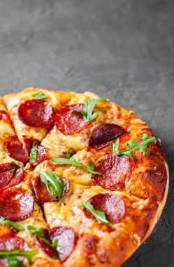 Mozzarella peyniri, salam, domates sos, biber, baharat ve taze roka ile biberli Pizza. İtalyan pizza koyu gri siyah arduvaz arka plan üzerinde