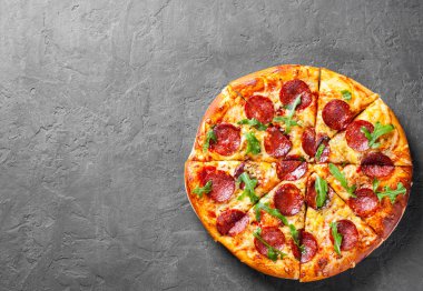 Mozzarella peyniri, salam, domates sos, biber, baharat ve taze roka ile biberli Pizza. İtalyan pizza koyu gri siyah arduvaz arka plan üzerinde