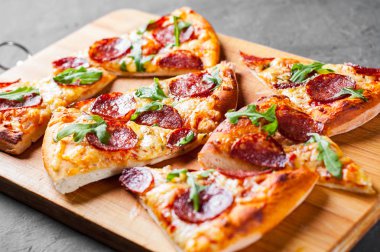 Mozzarella peyniri, salam, domates sos, biber, baharat ve taze roka ile biberli Pizza. İtalyan pizza koyu gri siyah arduvaz arka plan üzerinde