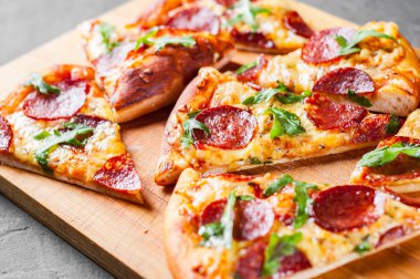 Mozzarella peyniri, salam, domates sos, biber, baharat ve taze roka ile biberli Pizza. İtalyan pizza koyu gri siyah arduvaz arka plan üzerinde