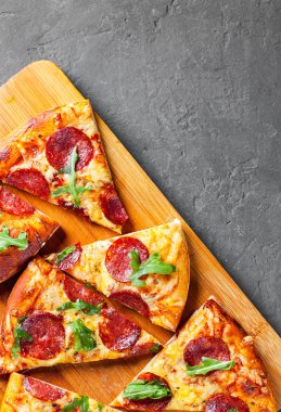 Mozzarella peyniri, salam, domates sos, biber, baharat ve taze roka ile biberli Pizza. İtalyan pizza koyu gri siyah arduvaz arka plan üzerinde