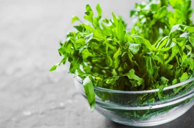 Koyu gri siyah arduvaz arka plan üzerine cam kapta taze Roka Salatası