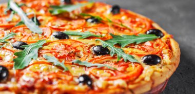 Pizza Mozzarella peyniri, domates, biber, zeytin, baharatlar ve taze roka ile. İtalyan pizza. Pizza Margherita veya koyu gri siyah arduvaz arka plan Margarita