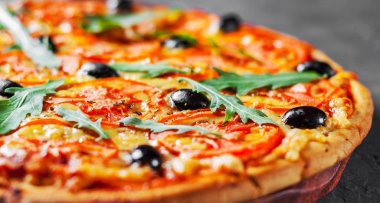 Pizza Mozzarella peyniri, domates, biber, zeytin, baharatlar ve taze roka ile. İtalyan pizza. Pizza Margherita veya koyu gri siyah arduvaz arka plan Margarita