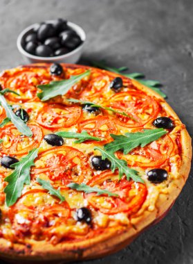 Pizza Mozzarella peyniri, domates, biber, zeytin, baharatlar ve taze roka ile. İtalyan pizza. Pizza Margherita veya koyu gri siyah arduvaz arka plan Margarita