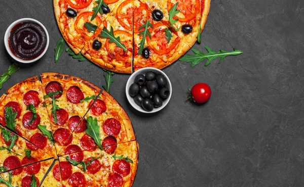 Pepperoni Pizza and Pizza with Mozzarella cheese, Tomatoes, pepper, olive, Spices and Fresh arugula. Pizza Margherita or Margarita on Dark grey black slate background