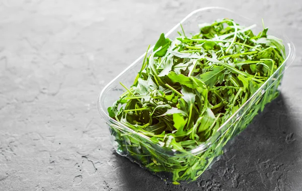 Foglie Rucola Verde Fresco Una Scatola Plastica Sfondo Grigio Scuro — Foto Stock