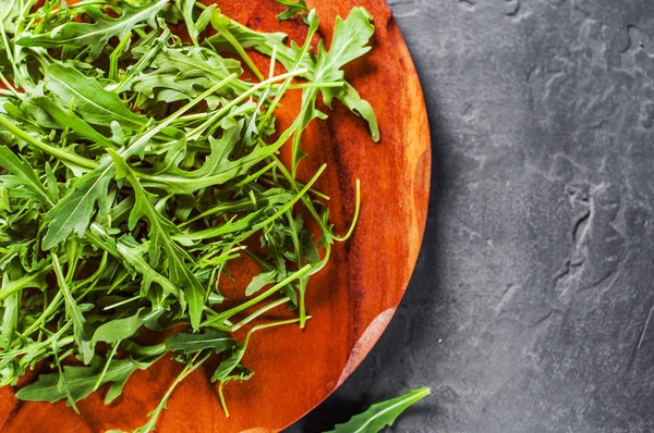 Rúcula Verde Fresco Hojas Plato Madera Sobre Fondo Pizarra Negra — Foto de Stock