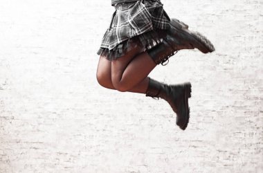 Siyah deri çizme genç kadın bacaklar gri duvar arka planda atlama