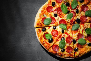 Mozzarella peyniri, salam, zeytin, biber, Baharat ve Taze ıspanak ile Pepperoni Pizza. Koyu gri siyah arduvaz arka plan üzerinde İtalyan pizza